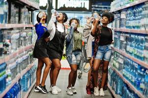 groupe de cinq femmes africaines avec des bouteilles d'eau en plastique au supermarché. photo