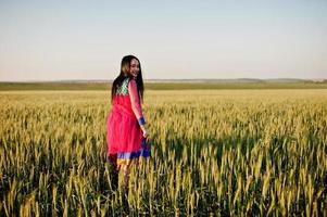 tendre fille indienne en sari, avec des lèvres violettes maquillées posées sur le terrain au coucher du soleil. modèle indien à la mode. photo