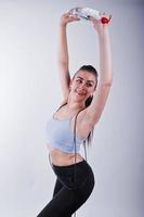 Cheerful attractive young fitness woman in top et leggings noirs avec corde à sauter et bouteille d'eau isolé sur fond blanc. photo