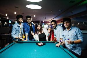 groupe d'amis asiatiques élégants portent des jeans jouant au billard au bar. photo