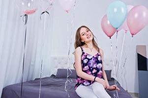 fille heureuse avec des ballons colorés sur le lit dans la chambre. célébrer le thème de l'anniversaire. photo