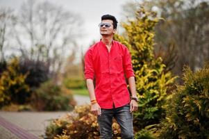 homme indien en chemise rouge et lunettes de soleil posées à l'extérieur. photo