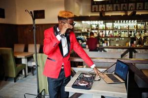 mode homme afro-américain modèle dj en costume rouge avec contrôleur dj. photo