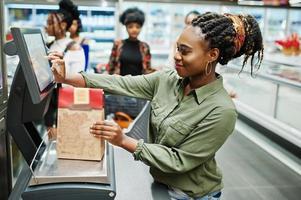 femme africaine avec boîte de poids de panier de réfrigérateur au supermarché. photo