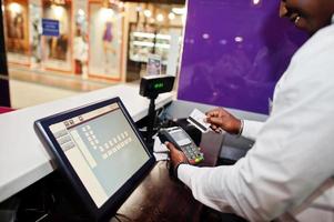 le barman afro-américain au bar utilise un terminal de carte de crédit sur le caissier. photo