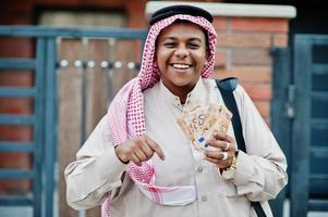 homme d'affaires arabe du moyen-orient posé dans la rue contre un bâtiment moderne avec sac à main noir et argent en euros. photo