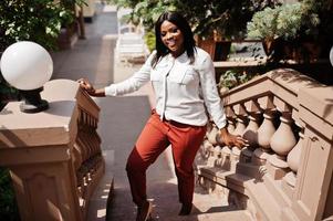 femme d'affaires afro-américaine formellement habillée en chemisier blanc et pantalon rouge. femme d'affaires prospère à la peau foncée. photo