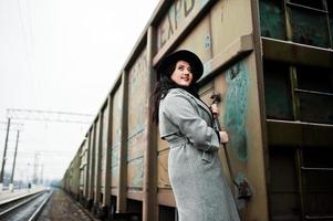 fille brune en manteau gris avec chapeau dans la gare. photo