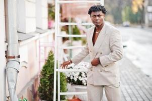 homme afro élégant en costume beige old school. jeune homme africain à la mode en veste décontractée sur torse nu. photo