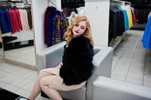 élégance fille blonde en manteau de fourrure au magasin de manteaux de fourrure et de vestes en cuir. photo