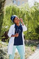 femme médecin afro-américaine avec stéthoscope posé en plein air. photo