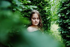 portrait d'une fabuleuse jeune fille en jolie robe avec une coiffure bouclée élégante posant dans la forêt ou le parc. photo