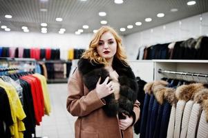 élégance fille blonde en manteau de fourrure au magasin de manteaux de fourrure et de vestes en cuir. photo