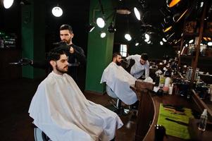 bel homme barbu au salon de coiffure, coiffeur au travail. photo