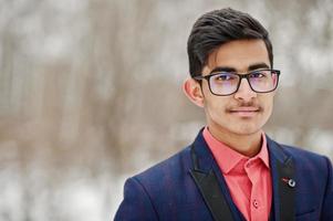 portrait en gros plan d'un étudiant indien élégant en costume, lunettes posées à la journée d'hiver en plein air. photo