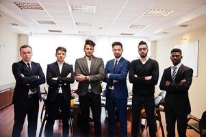 six hommes d'affaires multiraciaux debout au bureau avec les bras croisés. groupe diversifié d'employés masculins en tenue de soirée. photo