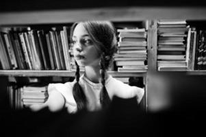 fille avec des nattes en blouse blanche à l'ancienne bibliothèque. photo