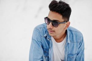 jeune homme indien décontracté en chemise de jeans bleu et lunettes de soleil posées le jour de l'hiver. photo