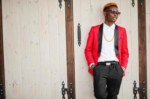 modèle d'homme afro-américain de mode en costume rouge, avec des cheveux en surbrillance et un sac à main posé dans la rue. photo