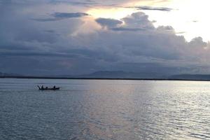 pêcheur sur son bateau au coucher du soleil. bateau de pêcheurs au coucher du soleil photo