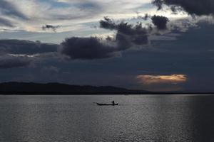 pêcheur sur son bateau au coucher du soleil. bateau de pêcheurs au coucher du soleil photo