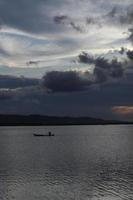 pêcheur sur son bateau au coucher du soleil. bateau de pêcheurs au coucher du soleil photo