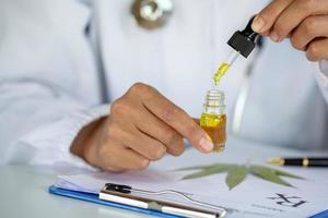 main de médecin tenant une bouteille d'huile de cannabis contre la plante de marijuana, pipette d'huile cbd. recette de cannabis à usage personnel, prescription légale de drogues légères.