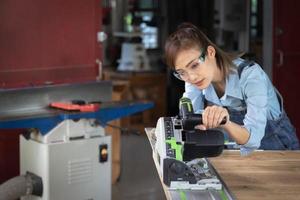 femme travaille dans un atelier de menuiserie. menuisier travaillant sur des machines à bois dans un atelier de menuiserie. photo