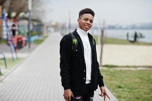 jeune garçon africain millénaire marchant dans la ville. heureux homme noir avec sac à dos de marijuana. notion de génération z. photo