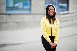 fille afro-américaine hipster portant un sweat à capuche jaune posant dans la rue. photo