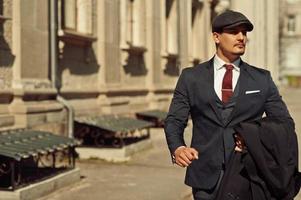 portrait d'un homme d'affaires arabe anglais rétro des années 1920 portant un costume sombre, une cravate et une casquette plate marchant dans les vieilles rues. photo