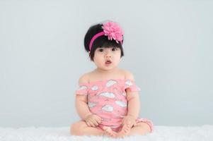 portrait d'un bébé asiatique mignon sur un tapis blanc, sourire nouveau-né pour prendre une photo