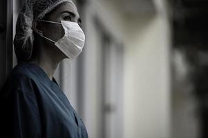 une infirmière asiatique fatiguée et déprimée porte un masque facial uniforme bleu assis sur le sol de l'hôpital, jeune femme médecin stressée par un travail acharné photo