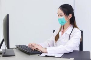femme médecin asiatique tape sur le clavier pour enregistrer des informations photo