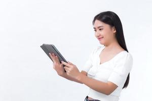un bel étudiant asiatique en chemise blanche regarde joyeusement la tablette dans sa main. sur fond blanc photo