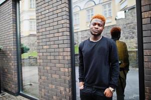 l'homme aux cheveux rouge africain porte une tenue noire posant à l'extérieur. photo