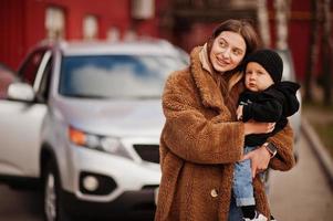 jeune mère et enfant se tiennent près de leur voiture suv. concept de conduite de sécurité. photo