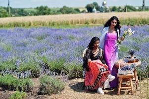 deux belles filles indiennes portent une robe traditionnelle indienne saree dans un champ de lavande violette. photo
