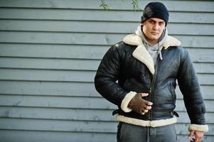 un homme sérieux arabe sur une veste en cuir et un chapeau noir copie son idole d'un film d'action. photo