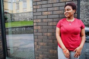 femme africaine porte un t-shirt rouge posant en plein air. photo