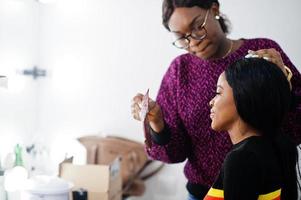 femme afro-américaine se maquillant par une maquilleuse au salon de beauté. photo