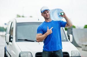 livreur devant une camionnette livrant des bouteilles d'eau montrant le doigt. photo