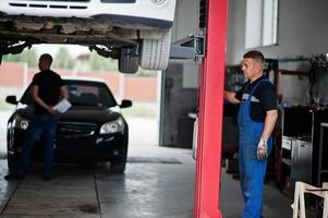 thème de la réparation et de l'entretien des voitures. mécanicien en uniforme travaillant dans le service automobile. photo