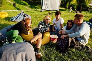 jeune groupe multiethnique de personnes regardant un film au pouf dans un cinéma en plein air. photo