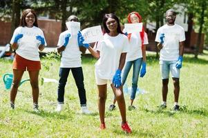 un groupe de volontaires africains heureux tient un tableau vierge avec de l'aide dans le parc. concept de volontariat, de charité, de personnes et d'écologie en afrique. photo