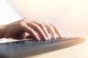 main de femme tapant sur le concept de clavier de recevoir ou d'envoyer une icône d'e-mail sur un bureau avec un ordinateur portable photo