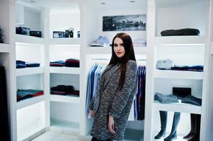 brune magnifique fille dans la boutique de vêtements décontractés et manteau gris. photo