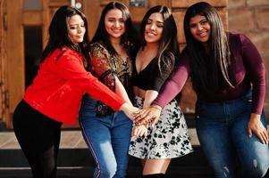 groupe de quatre filles latinos heureuses et jolies de l'équateur posées dans la rue et se tenant la main. photo