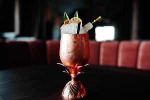 cocktail alcoolisé avec glace en verre bronze sur table de bar. photo