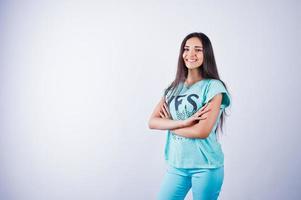 portrait d'une belle jeune femme en t-shirt bleu ou turquoise et pantalon posant en studio. photo